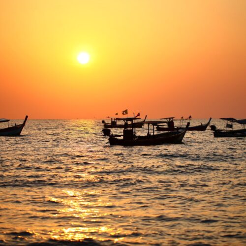 small boats floating on the water at sunset