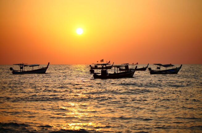 small boats floating on the water at sunset